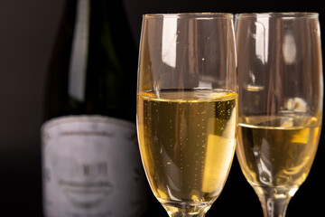 Elegant champagne bottle and two glasses filled with sparkling champagne, against a black backdrop. Ideal for New Year's Eve and holiday celebrations.