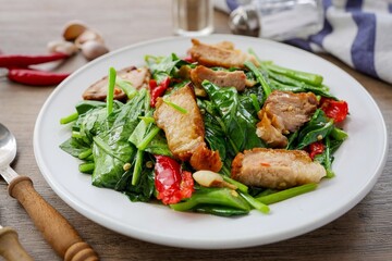 Stir fried Chinese Broccoli with crispy pork,Crispy pork with Chinese broccoli,Stir fried crispy pork in kale in a white plate on wooden background