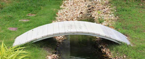 small bridge is over small stream of water in garden.