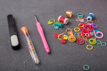 Crocheting tools kit. Set of crochet hook, thimble, pins, markers and other equipment for creative handicraft on grey background. Closeup