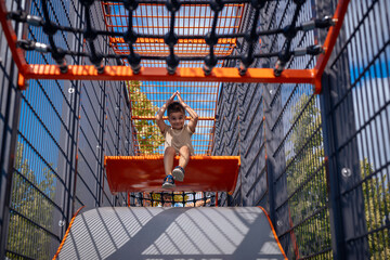 A joyful child plays enthusiastically on colorful playground equipment, showcasing pure fun and...