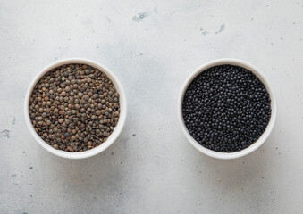 Bowls with dry raw black and green lentils seeds on kitchen table.Macro.