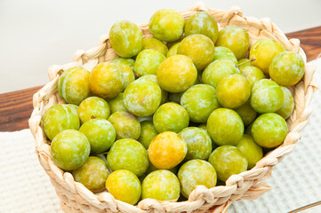 sweet yellow plums in a basket on the table. ripe plums of the Renclod variety
