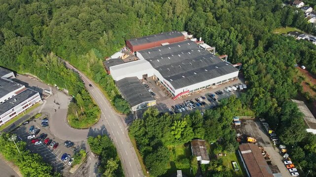 Beautiful aerial of a small factory in a rural area surrounded with green forests on a sunny summer day