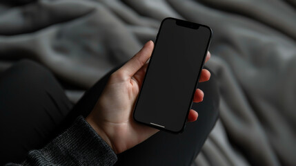 Close-up of a modern smartphone in hands on a gray plaid background. Black technology phone indoors. Concept of technology, modernity.