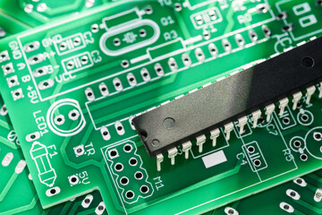 Microchip on a green printed circuit board with various soldering points.