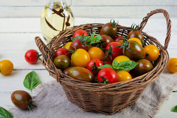 Multi-colored tomatoes in wickerwork basket. Different types of fresh tomatoes