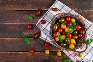 Multi-colored tomatoes in wickerwork basket. Different types of fresh tomatoes