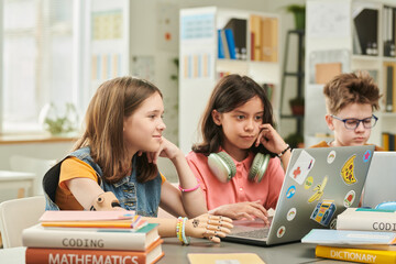 Colorful portrait of children using computers in school library with focus on young girl with arm...