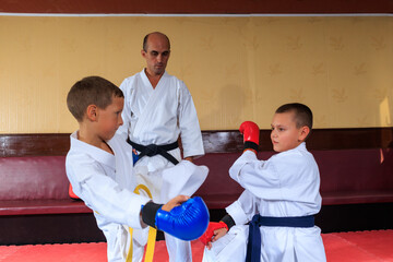 Athlete in blue pads throws a roundhouse kick at an athlete in red pads