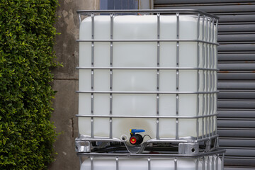 white ibc containers with steel shutter door of factory background, white plastic chemical tanks.