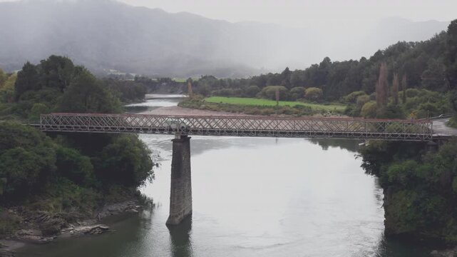 Aerial drone shot of a camper van crossing the Iron Bridge over the Buller River in New Zealands south island
