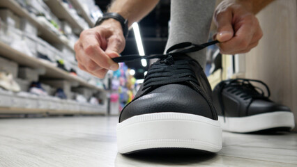 A male buyer tries on black leather boots in a shoe store close-up