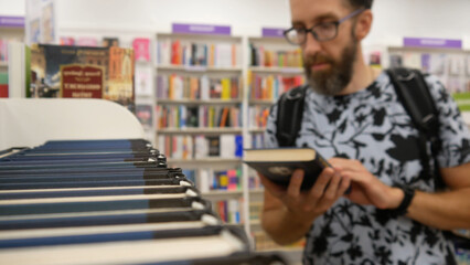 Close-up of a man choosing a book in a book shop or library 