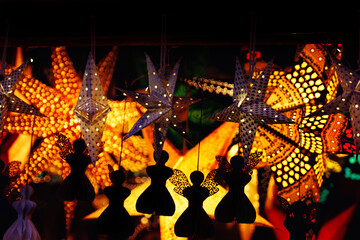 Close-up of beautifully lit star and angel ornaments at a evening Christmas market sale during the...