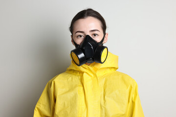 Worker in respirator and protective suit on grey background