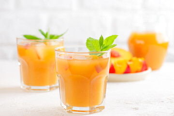 Peach and nectarine ice and mint drink on a light background. Homemade cold summer drink.