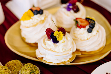 Słodki stół na weselu ślubne dekoracje bezy na złotym talerzu złota patera i desery cukiernictwo ozdoby cukiernicze beza z owocami i kwiatami