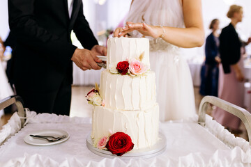 Para młoda kroi tory na weselu stół z tortem na sali pan młody i pani młoda moment torcik kremowy z kwiatami dekoracje ślubne © jusiamastalerz