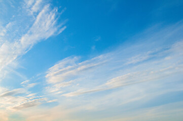 Naklejka premium Blue sky landscape with whitepastel clouds lit by soft sunlight