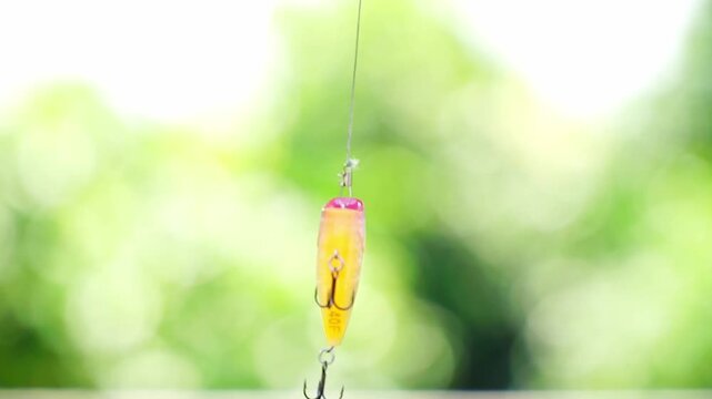 Treble hook popper artificial lure thighted on the fishing line. Yellow minnow bait.