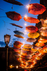 Colorful umbrellas and festive lights under dark blue evening sky of Catania, Italy. Magical travel destination of Sicily.