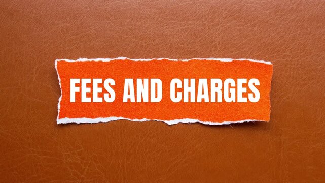 Fees and charges message writing on ripped torn orange paper on brown background. Conceptual fees and charges symbol. Copy space.