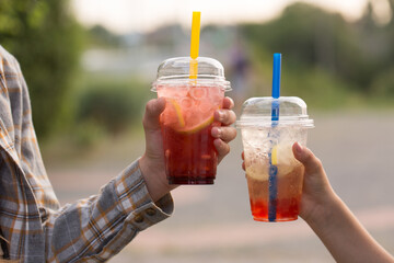 Two children drink bubble tea from plastic cups, close-up