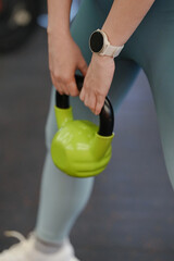 Closeup young woman doing exercise with kettlebell in gym.