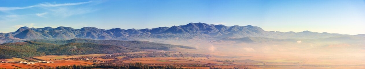 panorama of romania countryside in morning light. foggy weather. autumnal landscape in mountains. grassy field and rolling hills. rural scenery