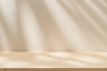 Empty table on stucco background with natural shadow on the wall. Stylish background for branding products, presentation, food and health care.	
