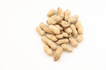 A small pile of peanuts in their shells, scattered on a white surface. A simple and natural snack.