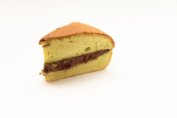 A triangular slice of chiffon cake, light green in color with a layer of chocolate filling, isolated on a white surface. A soft and airy dessert.
