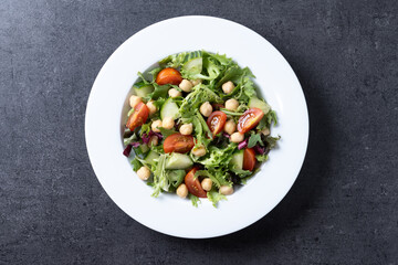Healthy chickpea salad with tomato,lettuce and cucumber on black slate background