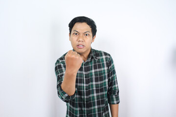angry asian man raising his fist at camera showing fighting gesture isolated