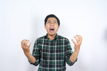 Fototapeta premium frustrated asian man wearing plaid flannel shirt raising hands and looking above with angry expression isolated