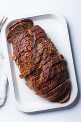 Sliced ​​rye bread with caraway seeds on white tray.