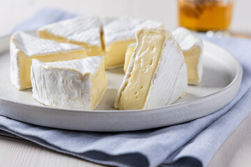 Close-up of Camembert Cheese Wheel with a Slice Removed, Honey Drizzle in Background