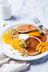 Breakfast pancakes with mango and passion fruit on white plate. Healthy vegan recipe.