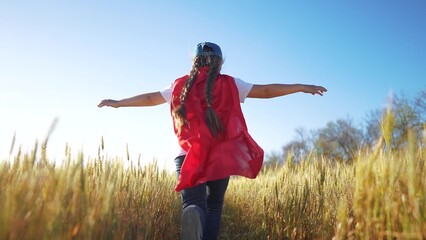 Superhero running through the wheat with his child. Hero super costume concept. girl runs across a field of wheat with a superhero. Girl runs fun through a field of wheat and runs into a superhero. © maxximmm