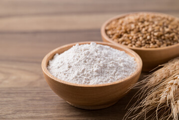 Wheat flour and wheat grain in bowl on wooden table, Food ingredient