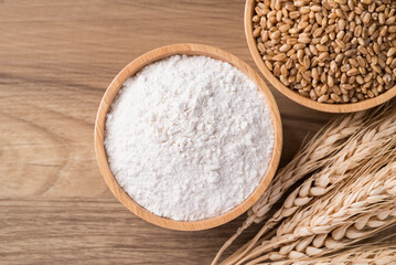 Wheat flour and wheat grain in bowl on wooden background, Food ingredient, Table top view