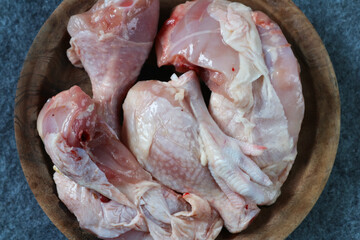 Pieces of raw chicken on a wooden plate on gray background