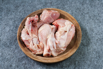 Pieces of raw chicken on a wooden plate on gray background