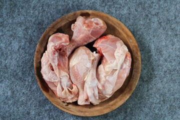 Pieces of raw chicken on a wooden plate on gray background