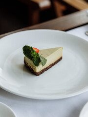 delicious cake with green cream, topped with fresh, fragrant strawberries and layered with black cake, is served on a beautiful white plate in a cozy, charming café