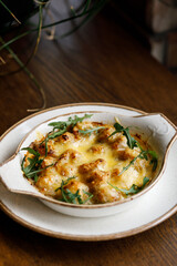  delicious dish with crispy potatoes, fresh vegetables, fragrant herbs, and creamy cheese on a beautiful black plate in a cozy, charming café.