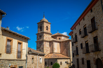 Fototapeta premium Side view of the parish church of Santa María, Sigüenza, Guadalajara, Castilla-La Mancha, Spain, with its bell tower as the main attraction from the streets of the town.