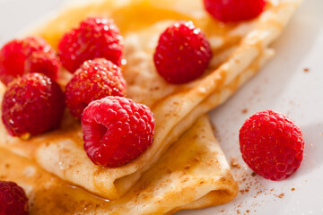 Delicious pancakes with fresh raspberries and honey