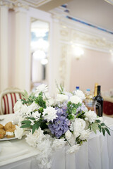 The festive table in the restaurant is decorated with a beautiful bouquet of white flowers.